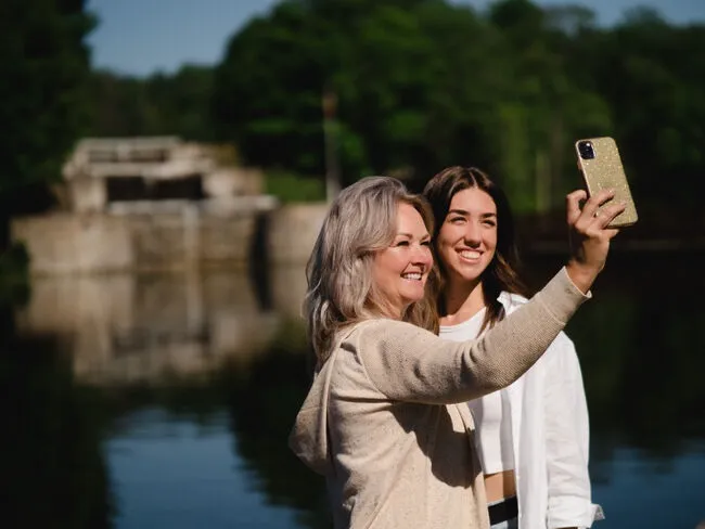 2 people taking a selfie in front of a lake