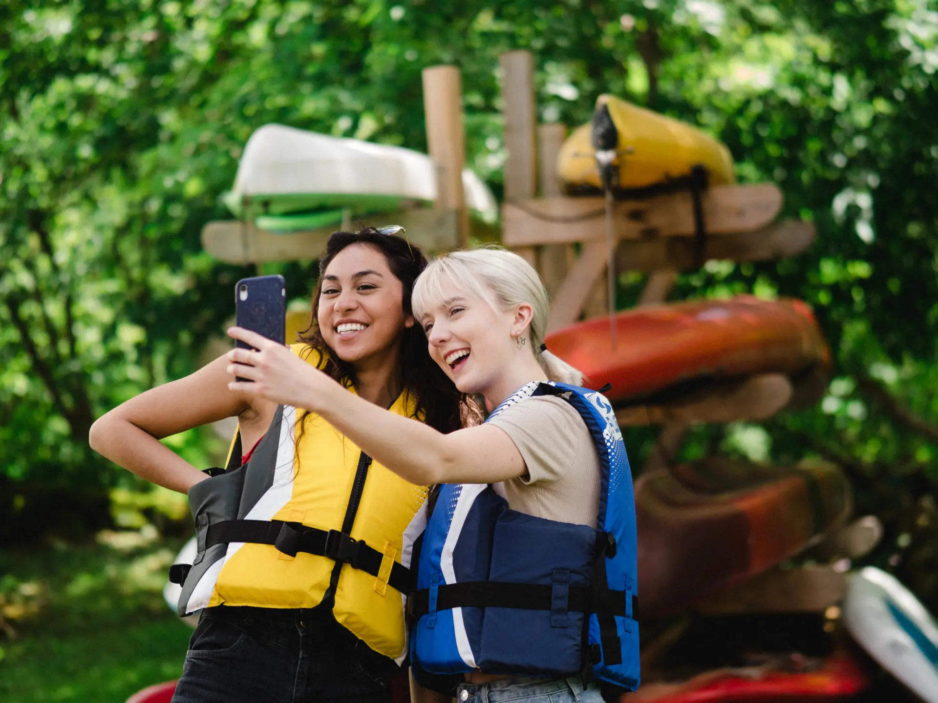 two girls taking selfie in front of kayaks